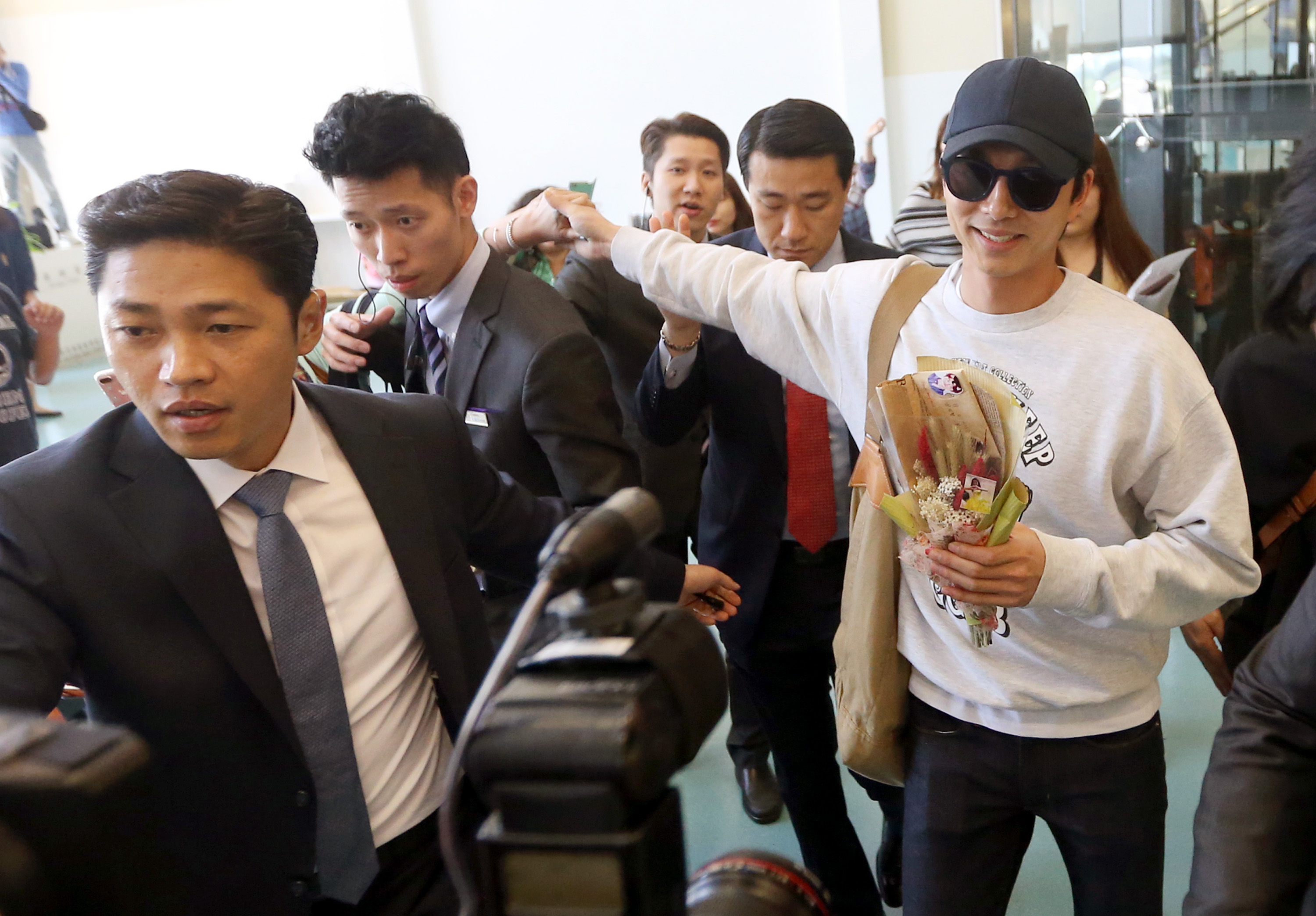 B3 桃園機場 韓星孔劉30日離台，登機前粉絲隔著保鑣人牆爭相握手送禮物。（范揚光攝）