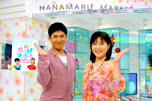 岡江久美子（右）與藥丸裕英搭擋主持TBS電視台生活資訊節目《はなまるマーケット》（Hanamaru Market），節目開始時必做「OPEN」手勢。（來源：ORICON NEWS，https://www.oricon.co.jp/news/2022786/photo/1/）